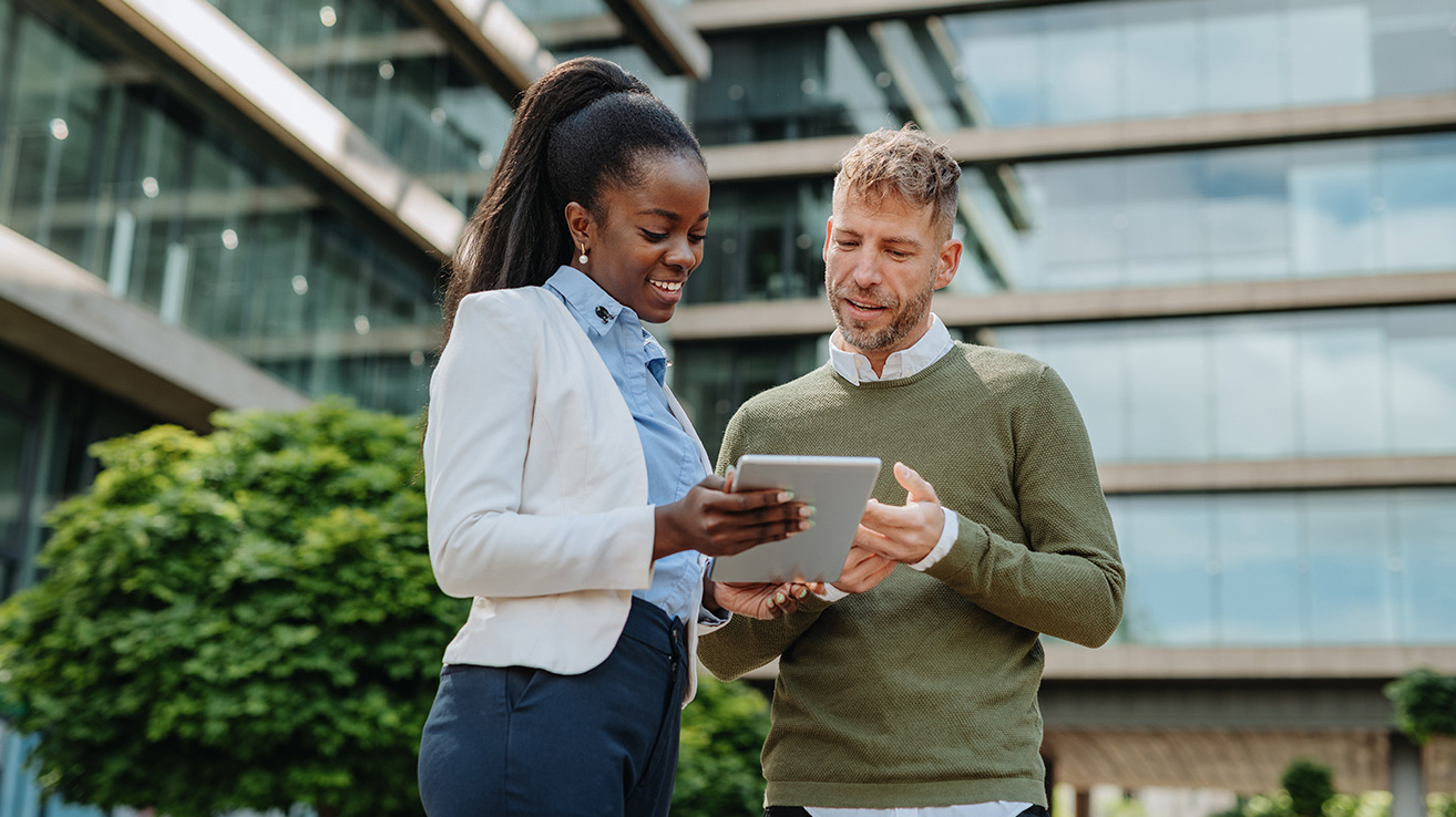 Woman and man review a tablet together outside an office building - Pavion Fire Safety, Integration, and Security